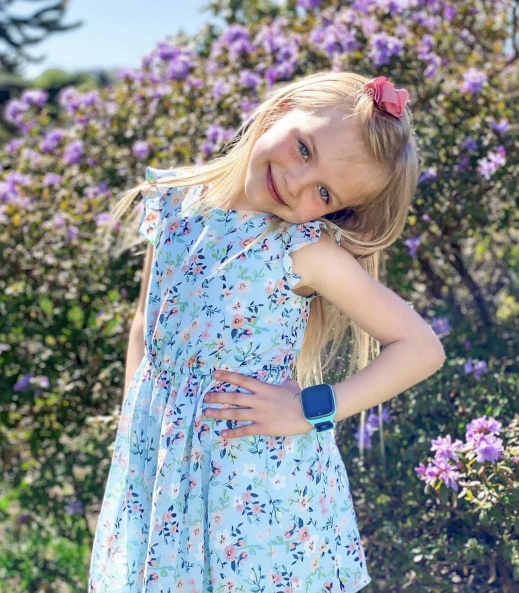 smilende jente med en turkis xplora klokke på venstre arm.